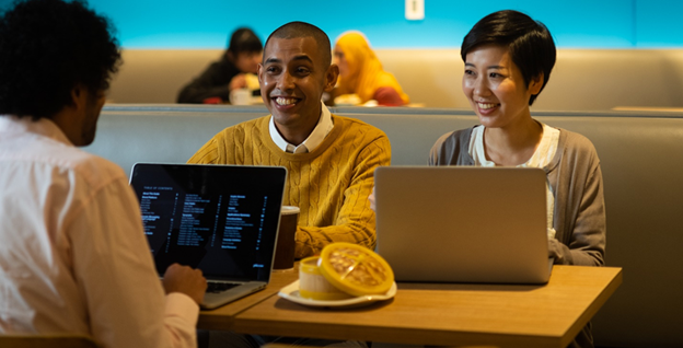 A group of people sitting at a table with laptops

Description automatically generated with medium confidence