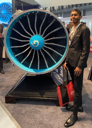 A person standing next to a large blue and white jet engine

Description automatically generated